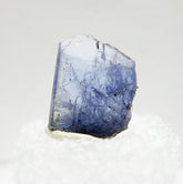 Close-up view of specimen of blue tanzanite crystal on white background