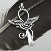 Silver Egyptian Ankh with wings and Eye of Horus pendant on black feather with light background.