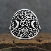 Front view of oxidized sterling silver ring with Celtic Tree of Life design and crescent moons and pentagram resting on rustic wood surface with dark grey background.