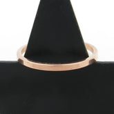 Slender flat faced copper band ring hung on a black cone with a white background.