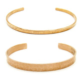 Front view of both a gently hammered narrow copper open-cuff bracelet above and a gently hammered wide copper open-cuff bracelet on a white background