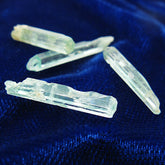 Close up perspective view of 4 long narrow Nigerian emerald crystals randomly arranged on dark background