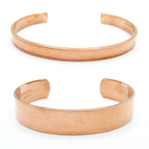 Front view of two plain polished copper open cuff bracelets, one narrow (above), one wide (below), on white background