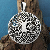 Front view of cut-out Tree of Life pendant on wood branch with green background.