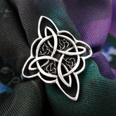 Fancy silver Witch's Knot ring on dark colorful cloth background
