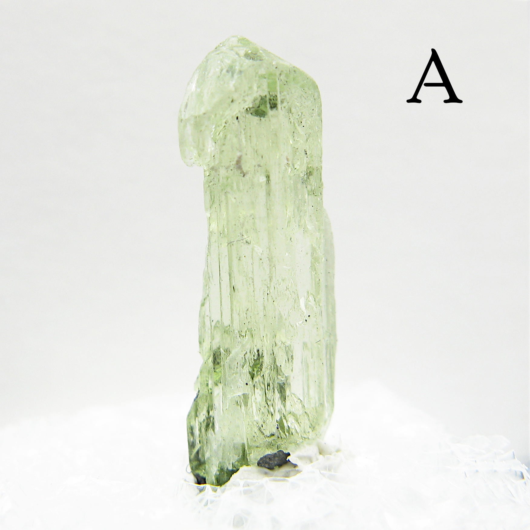 Tall Light green Diopside crystal against light background