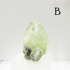 Short oval Light green Diopside crystal against light background