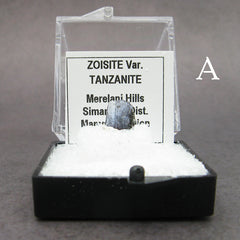 Front view of specimen of blue tanzanite crystal labeled in plastic box on dark background