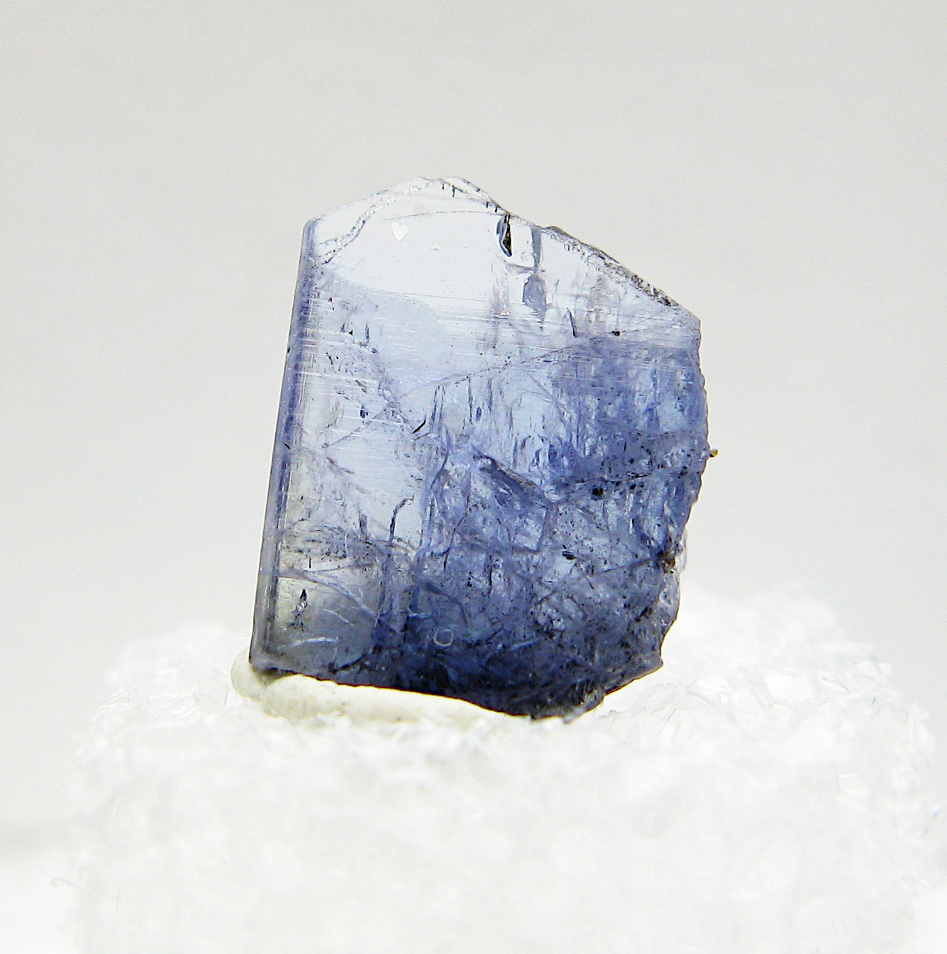 Close-up view of specimen of blue tanzanite crystal on white background