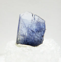 Close-up view of specimen of blue tanzanite crystal on white background