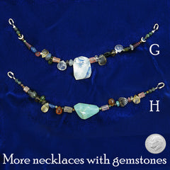 Labeled photo of two colorful necklaces strung with natural gemstones - one large gemstone at the center of each - neatly arranged on dark blue cloth background with a US dime to show scale