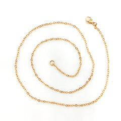 A delicate gold chain necklace with a lobster clasp, coiled on a plain white background.