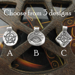 Handmade silver charms with inscribed pentagram, witch's knot, evil eye arranged in line and labeled on dark wood background