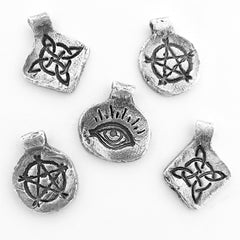 Handmade silver charms with inscribed pentagram, witch's knot, evil eye randomly arranged on white background
