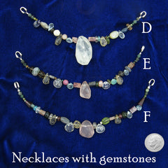 Labeled photo of three colorful necklaces strung with natural gemstones - one large gemstone at the center of each - neatly arranged on dark blue cloth background with a US dime to show scale