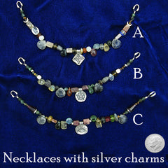 Labeled photo of three colorful necklaces strung with natural gemstones and silver charms with Witch's Knot, Pentagram and Evil Eye designs neatly arranged on dark blue cloth background with a US dime to show scale