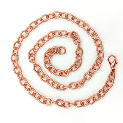A copper chain necklace with a lobster clasp, coiled in a spiral pattern on a plain white background.