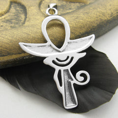 Rear view of silver Egyptian Ankh with wings pendant leaning on golden stone and black feather with light background