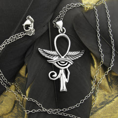 Silver Egyptian Ankh with wings and Eye of Horus pendant on silver chain  on black feather with golden stone background