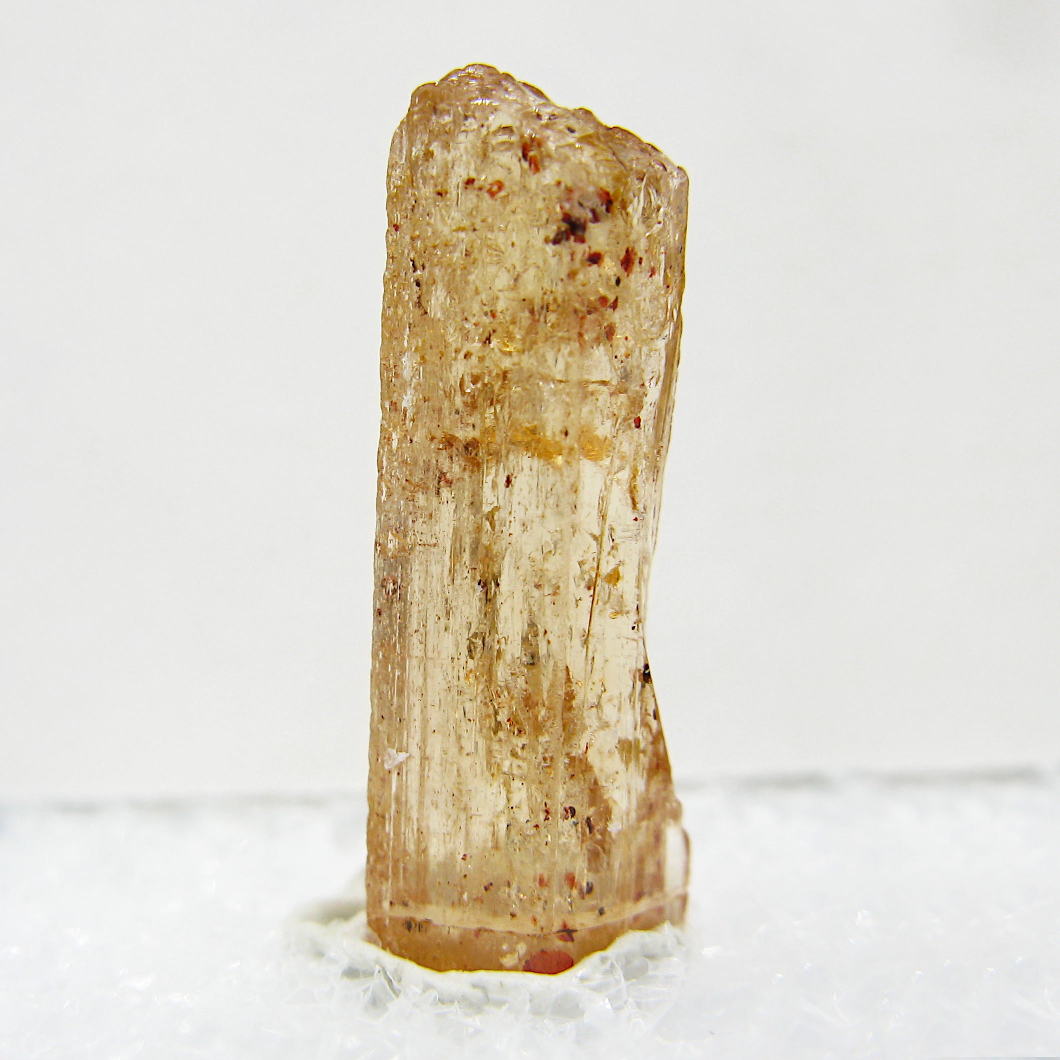Close-up of specimen of Brazilian 'honey' topaz gemstone on white background.