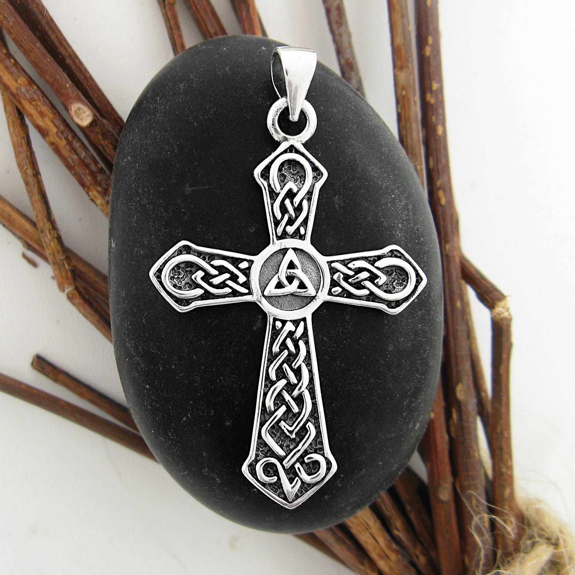 Silver cross pendant with Celtic design on a black stone with a natural background