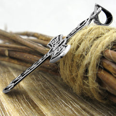 Side view of silver pendant with Celtic design on a wooden surface with twine