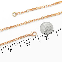 A copper chain necklace with a lobster clasp, shown alongside a US dime for scale and a black ruler measuring in inches on a white background.
