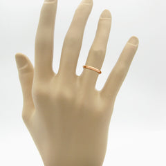 Mannequin's hand wearing a domed copper band ring against a white background.