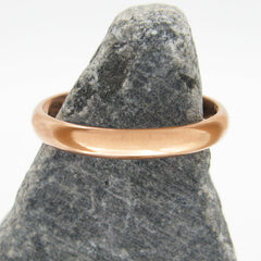 Domed copper band ring on a dark triangular stone against a white background.