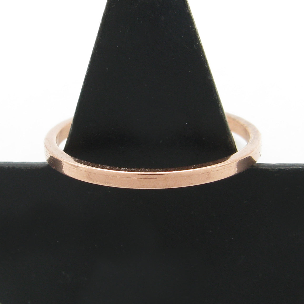 Slender flat faced copper band ring hung on a black cone with a white background.