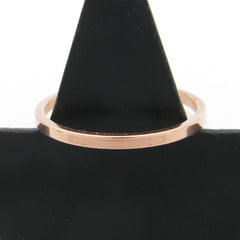 Slender flat faced copper band ring hung on a black cone with a white background.