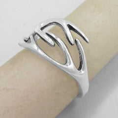 Side view of a polished silver ring with a deer's antlers design wrapped around an ivory colored candle with a plain gray background