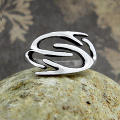 Front view of a polished silver ring with a deer's antlers design resting on a round stone with a brown floral background