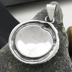 Rear view of silver  pendant lying on a stone with white and black background.