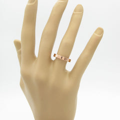 Flat copper band ring on mannequin's hand against white background.