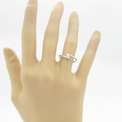 A silver ring with a sleek modern lightning bolt/thunderbolt symbol that is  minimalist and worn on a hand.