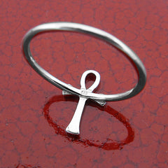 Back/inside view of a silver ring in the shape of an Egyptian ankh symbol inscribed with 925 and lying flat on a glossy dark red crackled ceramic surface.
