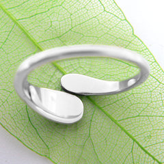 Back/inside view of a wrap-around two-tiered silver ring on lacy green leaf with white background