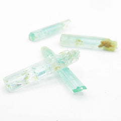 Close up perspective view of 4 long narrow Nigerian emerald crystals randomly arranged on white background