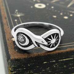 Overhead view of Silver Figure of Eight Snake Ring with Crescent Moon and Sun on black wood background with copper accent.