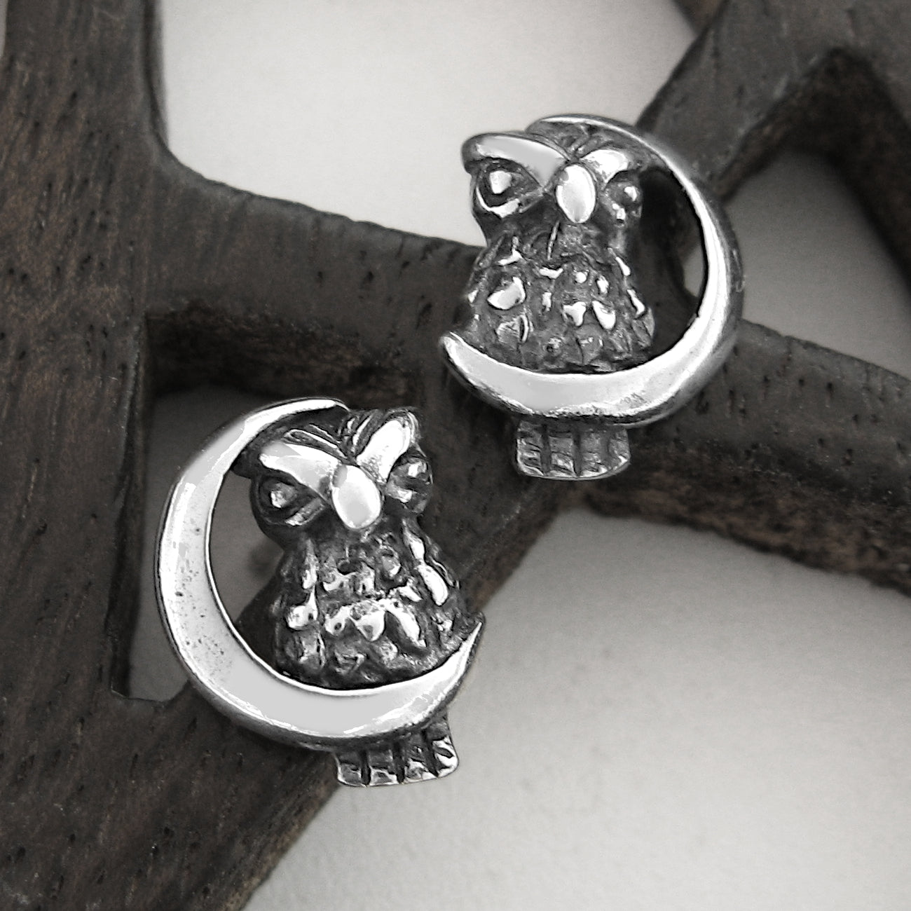 Silver owl and crescent moon earrings on a wood pentagram.