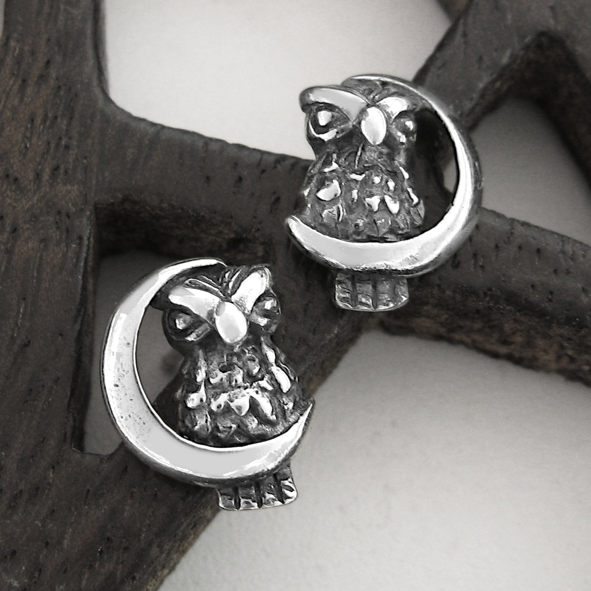 Silver owl and crescent moon earrings on a wood pentagram.