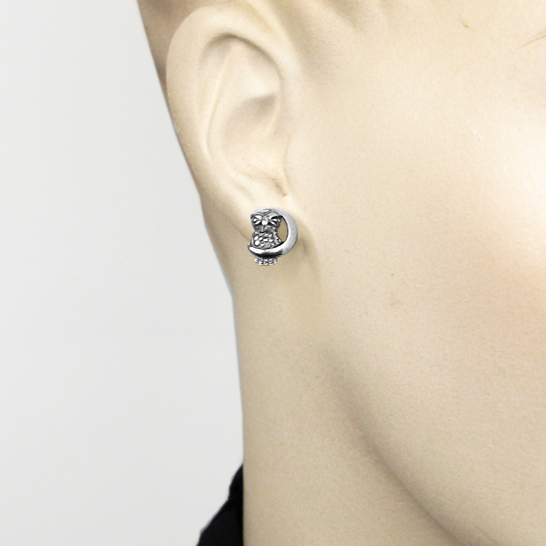 Close up of a mannequin wearing a silver owl and crescent moon earring.