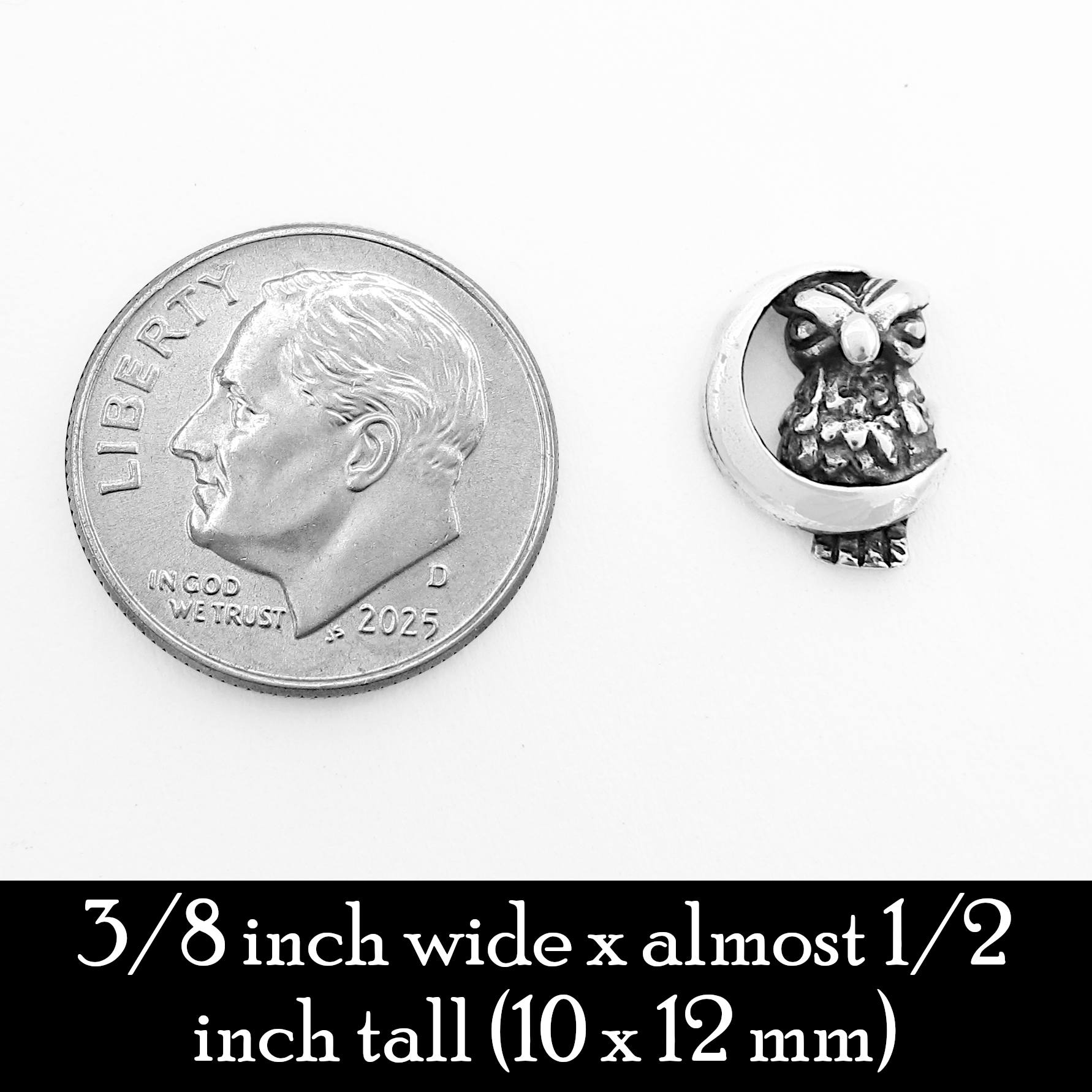 A silver owl and crescent moon earring shown with a dime for scale on white background.