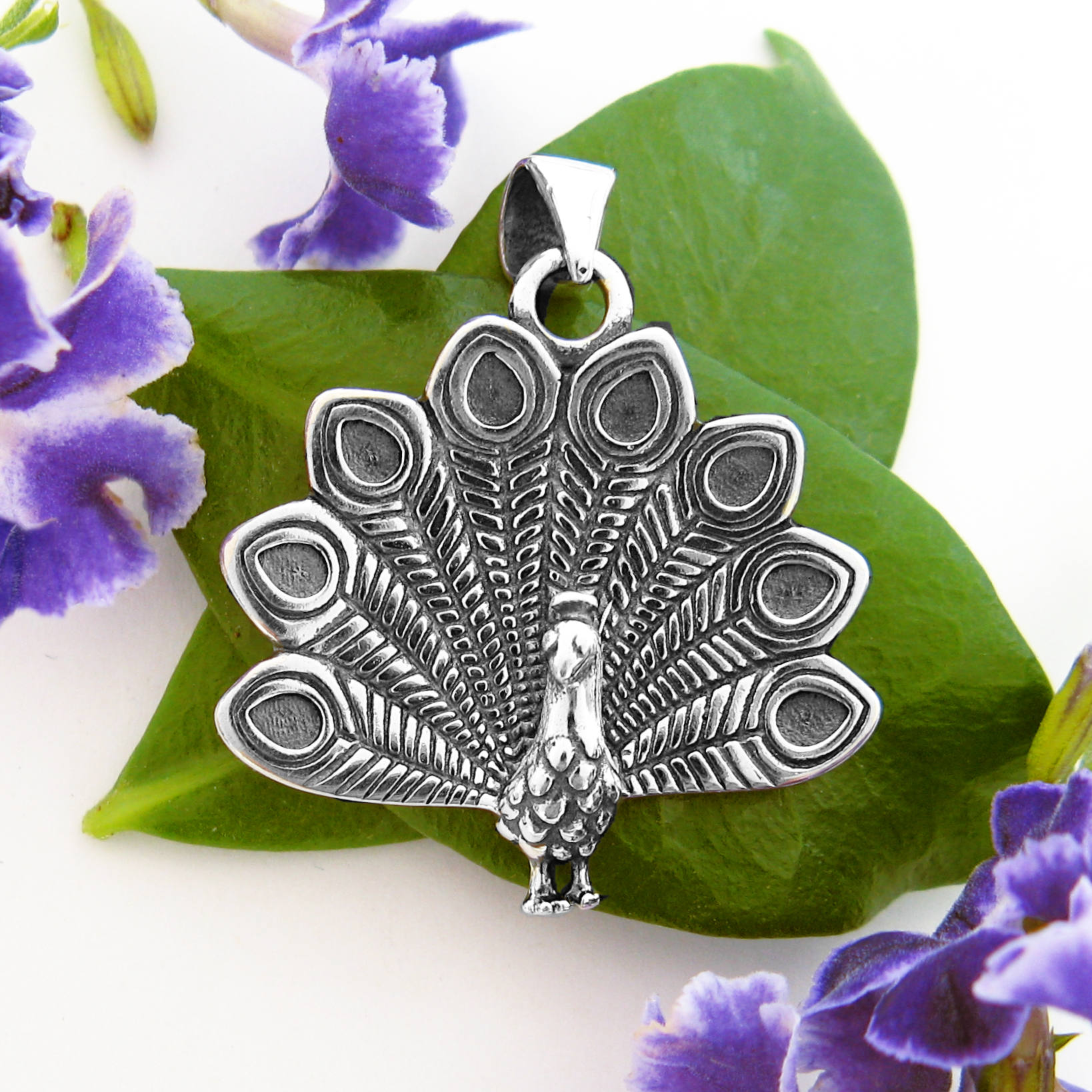 Nature-inspired sterling silver peacock pendant with detailed feathers fanned out open oxidized finish.