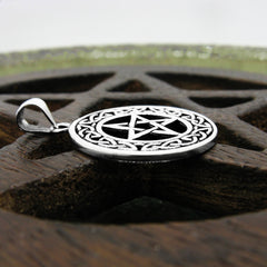 Side view of silver pentacle necklace with knotwork frame on wooden background