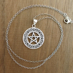 Pentagram pendant shown with optional chain on wooden background