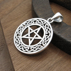 Close‑up of silver pentacle necklace with knotwork frame on wooden background