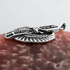 Side view of silver pendant with Egyptian design on red surface with light background