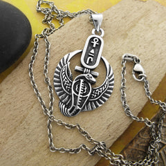 Silver pendant with Egyptian design with chain on wood background